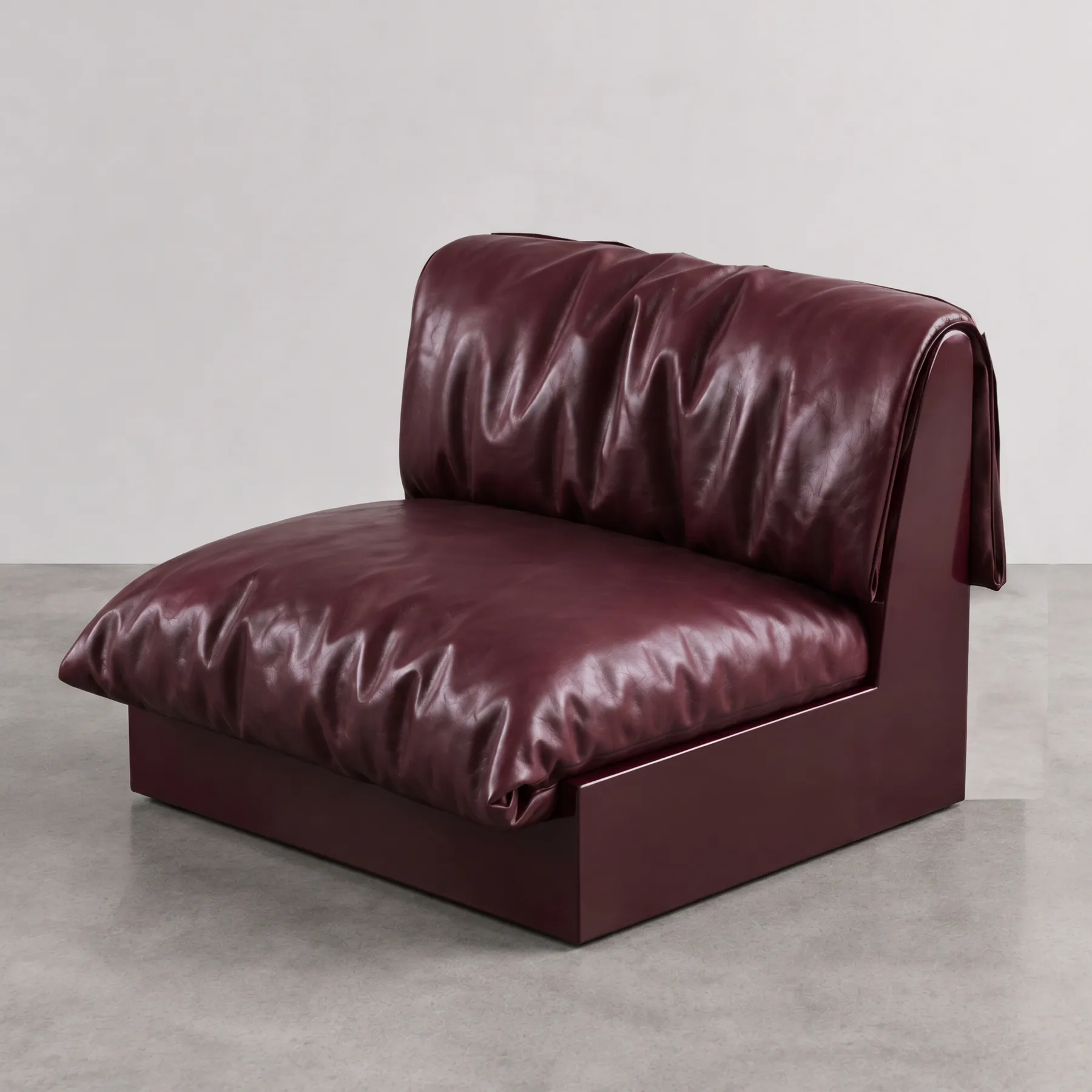 Undone Seat, a burgundy leather armchair with a loosely draped back, in a grey studio