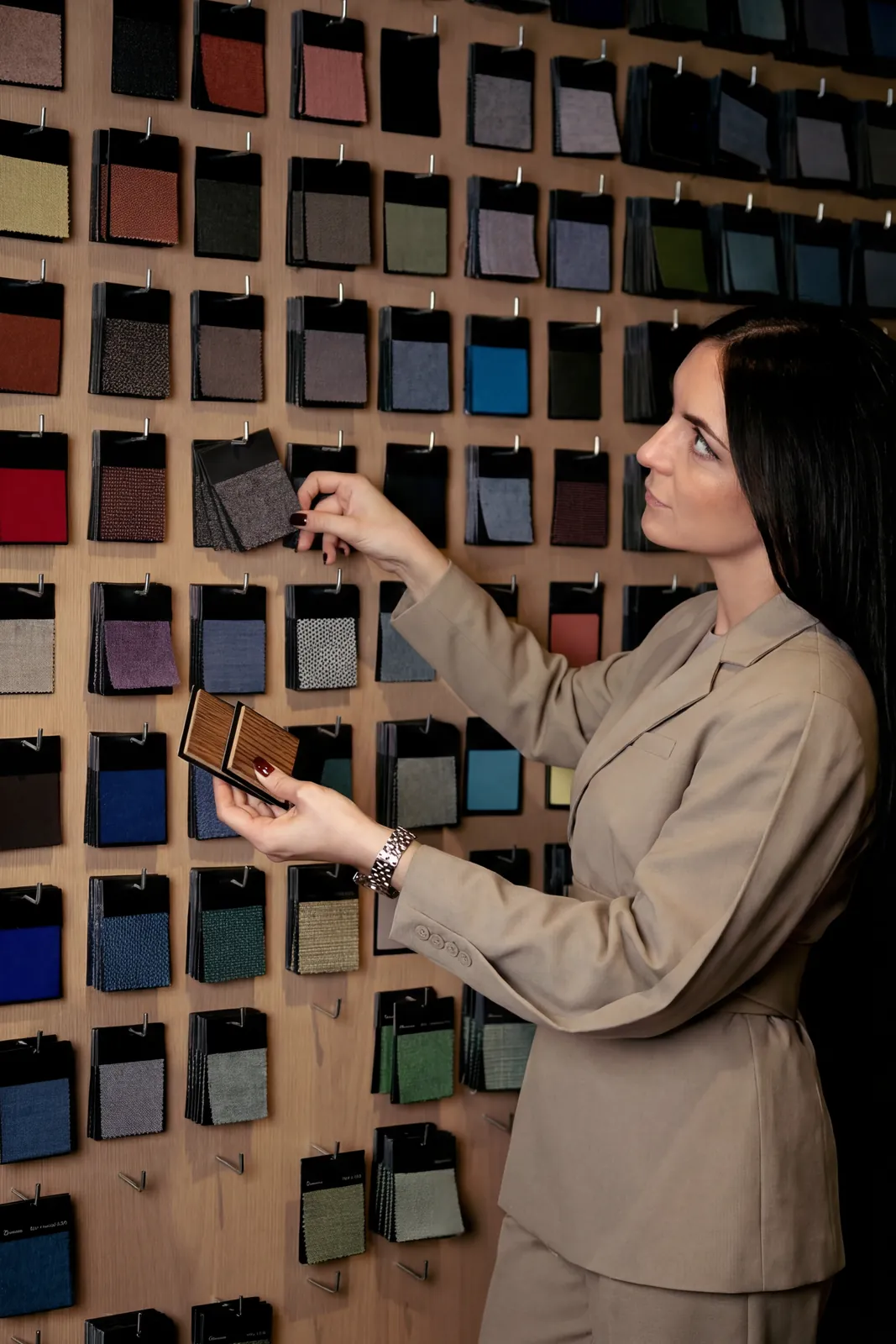 Morgane Avéus in a beige blazer holding fabric swatches against a wall of samples